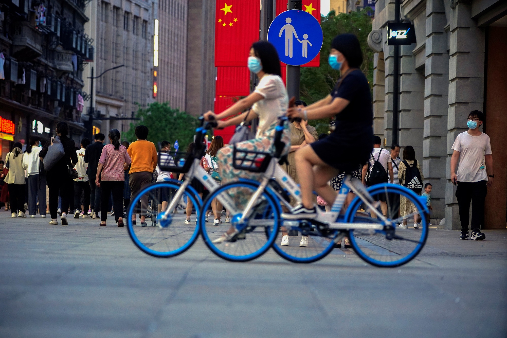 أشخاص يرتدون الكمامات ويركبون درجات في أحد الشوارع، في شنغهاي، الصين، 10 أيار/ مايو 2021. (رويترز)
