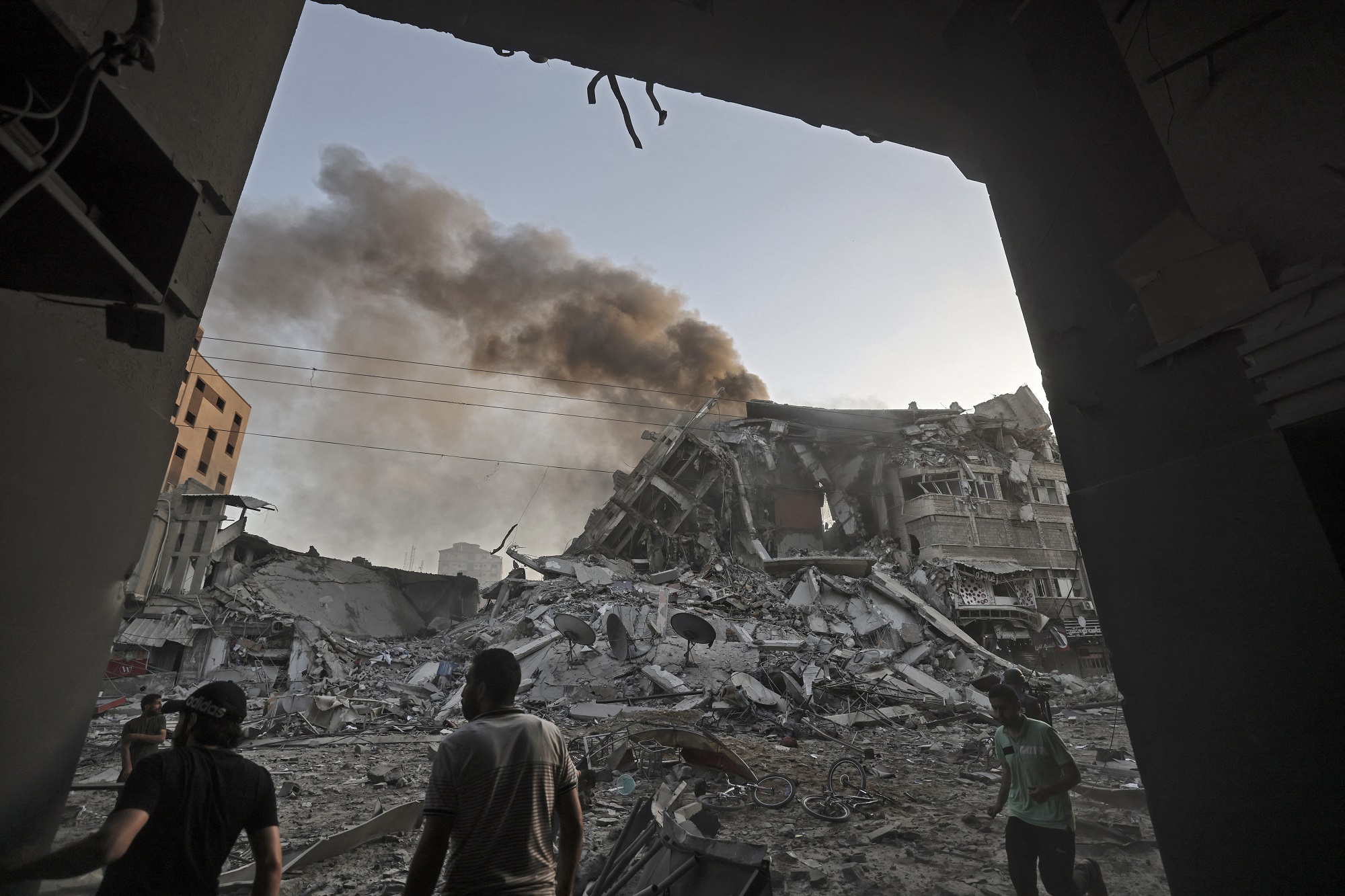 تجمع وسط الأنقاض أمام برج الشروق الذي انهار بعد استهدافه بغارة جوية إسرائيلية في قطاع غزة. 12 مايو/أيار 2021. (أ ف ب)