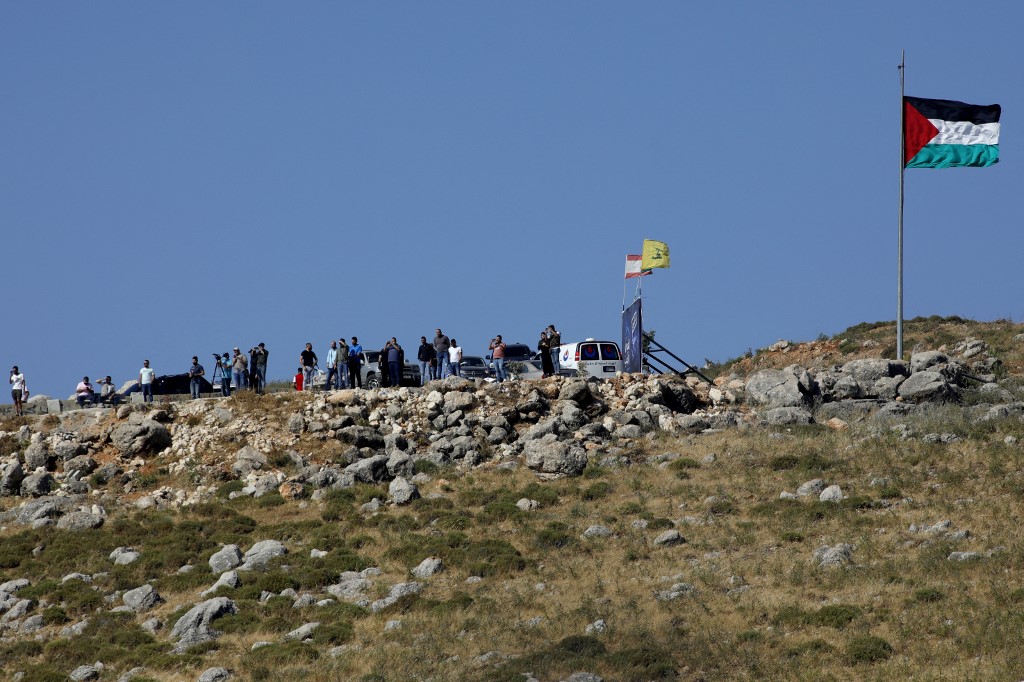 صورة من بلدة المطلة شمال الأراضي الفلسطينية المحتلة، قرب الحدود مع لبنان، لأشخاص يراقبون مسيرة مؤيدة للفلسطينيين في منطقة الخيام اللبنانية. 14/05/2021. (جالا مرعي / أ ف ب)