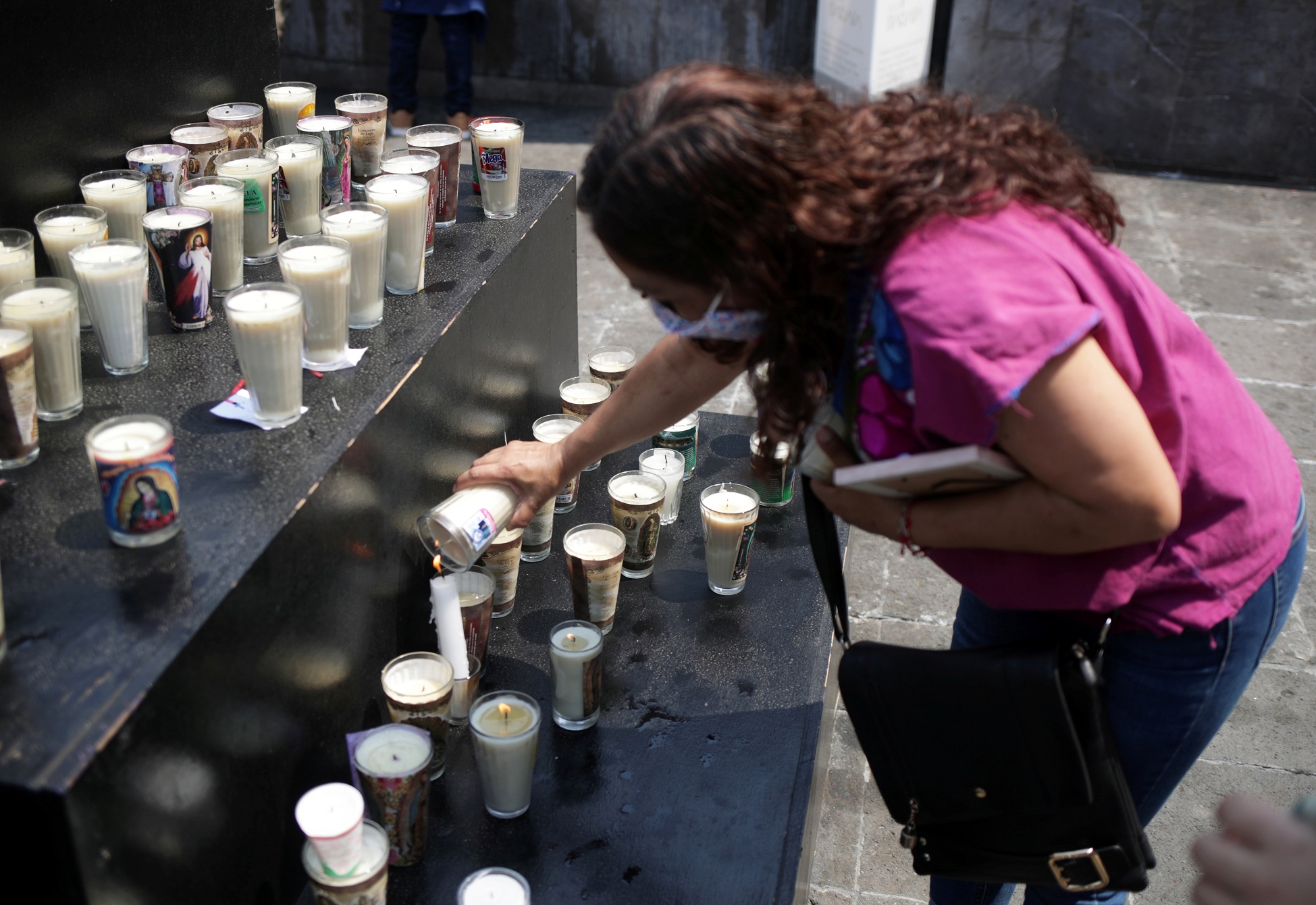 امرأة تضع شمعة في نصب تذكاري مخصص لضحايا كورونا في مكسيكو سيتي، المكسيك، 25 نيسان/ أبريل 2021