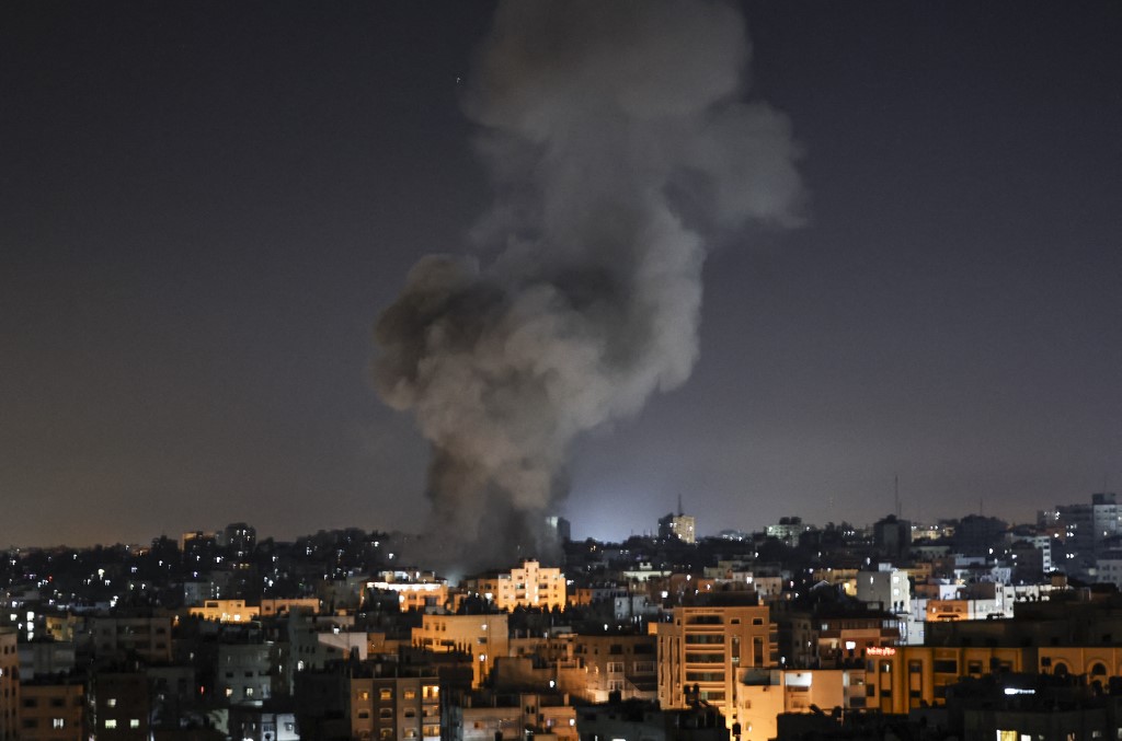 دخان يتصاعد فوق المباني بعد غارة جوية إسرائيلية على مدينة غزة في قطاع غزة في وقت مبكر من 15 أيار/مايو 2021. (أ ف ب)