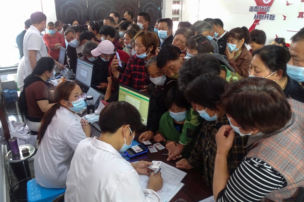 يسجل الأشخاص المعلومات أثناء استعدادهم لتلقي لقاح لفيروس كورونا، شرقي الصين، 13 مايو 2021. (رويترز)