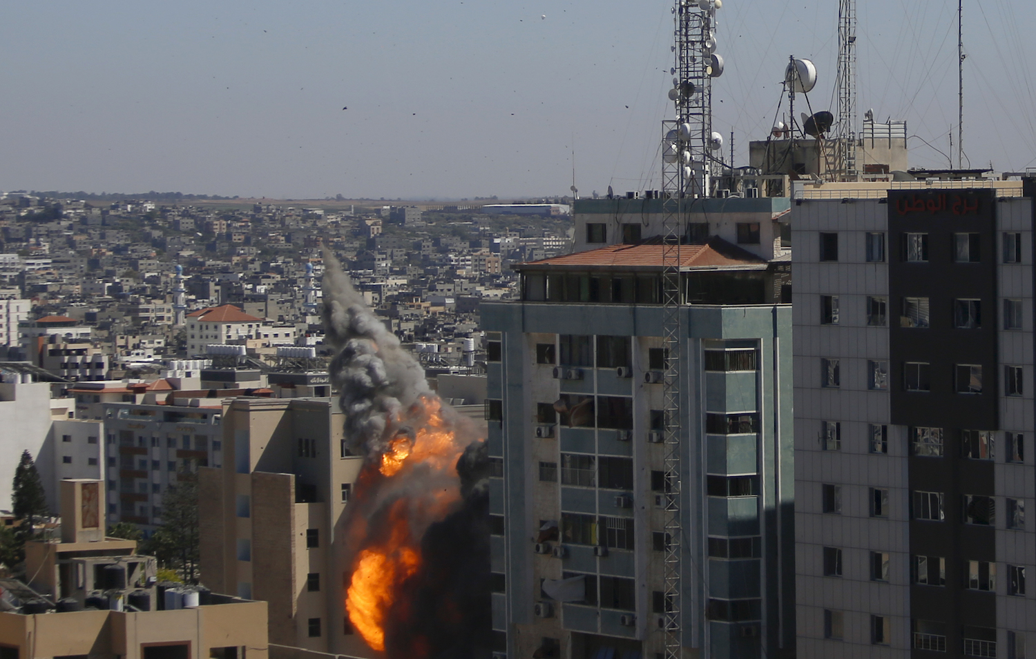 اندلاع النيران من برج الجلاء بعد تدميره بغارة جوية إسرائيلية على مدينة غزة، 15 أيار/مايو 2021. (وفا)