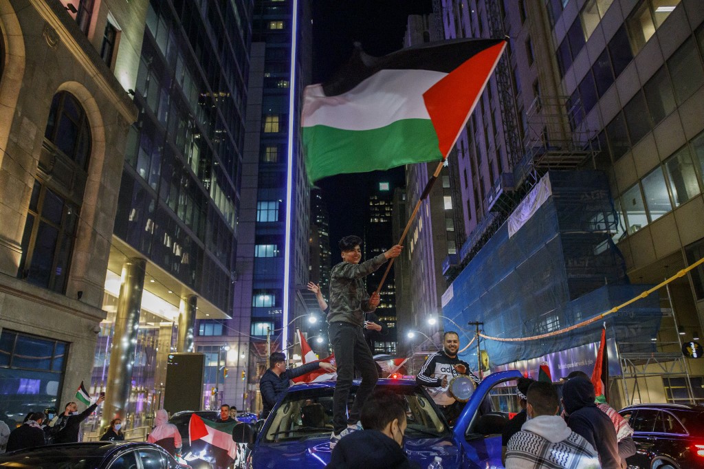 أشخاص يلوحون بالأعلام الفلسطينية، خلال مظاهرة للتعبير عن الدعم لشعب فلسطين، كندا، 15 مايو 2021. (أ ف ب)