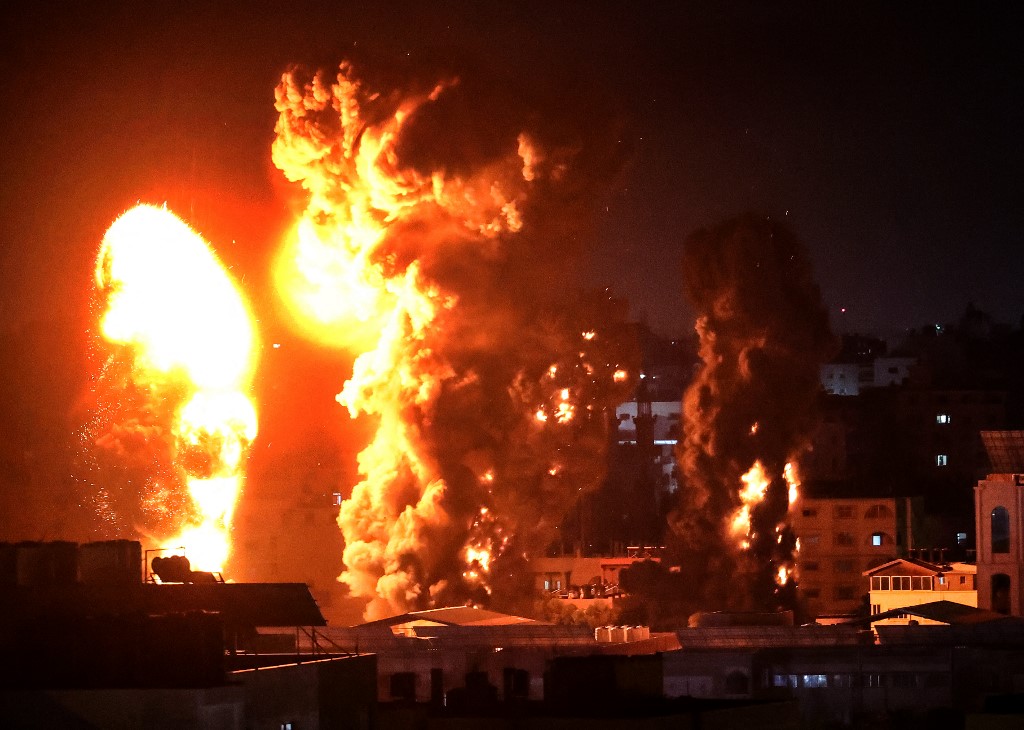 تصاعد النيران والدخان فوق المباني في مدينة غزة، جراء استهداف طائرات الاحتلال الإسرائيلي القطاع الفلسطيني، 17 مايو 2021. (أ ف ب)