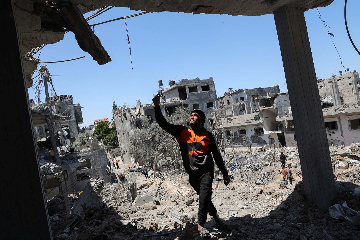 رجل فلسطيني يشير إلى موقع منازل مدمرة في أعقاب القصف الجوي والمدفعي الإسرائيلي مع استمرار الصراع الفلسطيني الإسرائيلي، شمالي قطاع غزة، 14 أيار/مايو 2021. (رويترز)