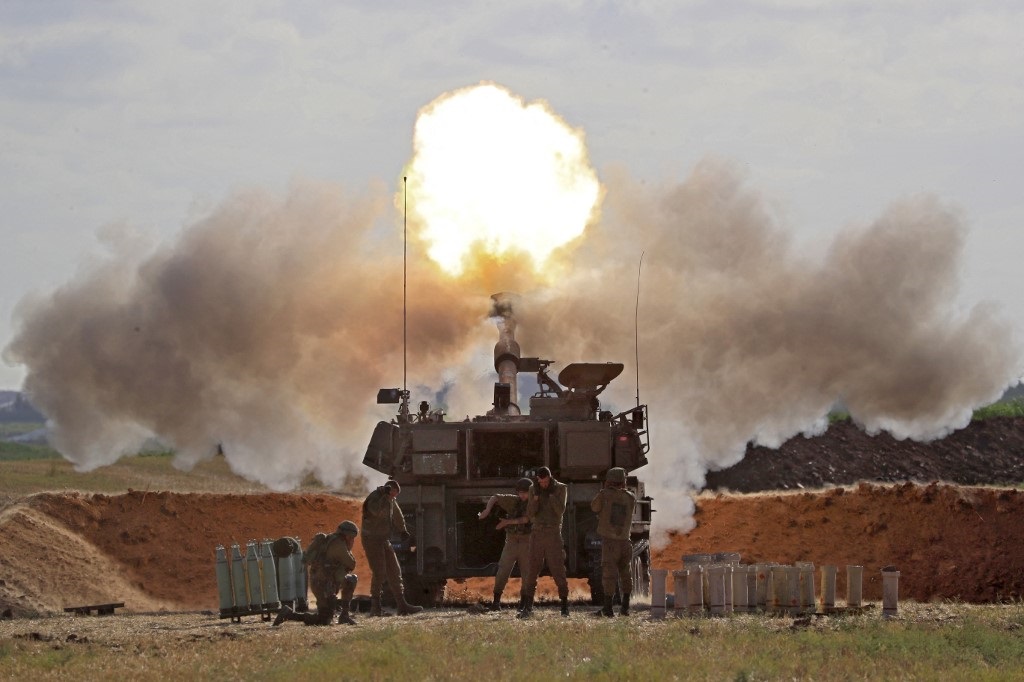 جنود إسرائيليون يطلقون قذيفة هاوتزر ذاتية الدفع عيار 155 ملم باتجاه قطاع غزة من موقعهم على طول الحدود مع القطاع الفلسطيني، 17 أيار/مايو 2021. (أ ف ب)