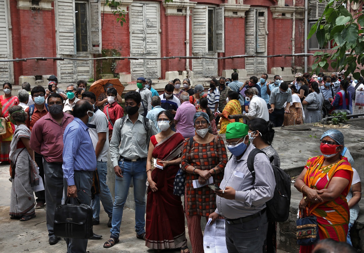 أشخاص يرتدون كمامات للوجه ينتظرون تلقي جرعتهم الثانية من اللقاح، خارج مركز التطعيم في كولكاتا ، الهند ، 12 أيار/مايو 2021. (رويترز)