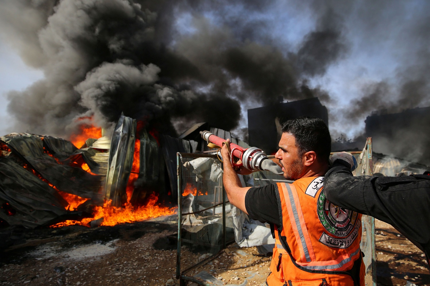إطفائي فلسطيني يشارك في جهود إخماد حريق في مصنع إسفنج بعد أن أصابته قذائف مدفعية إسرائيلية شمالي قطاع غزة . 17 أيار/مايو ، 2021. (رويترز / أشرف أبو عمرة)