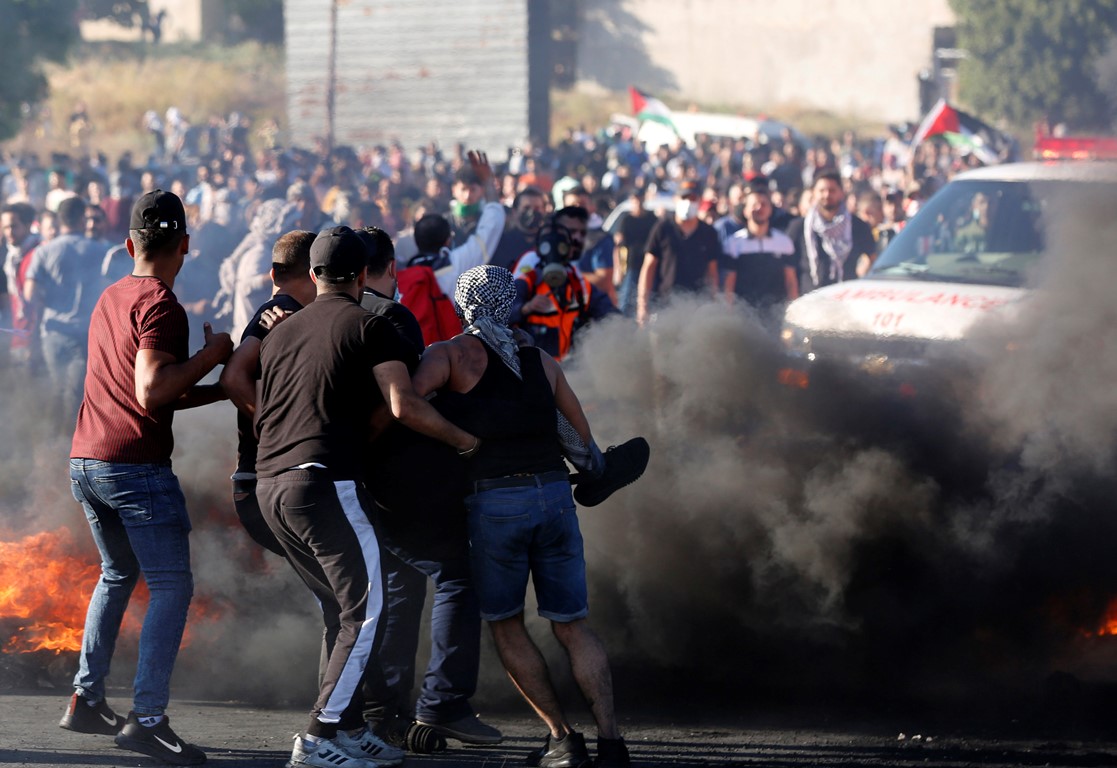 شبان يحملون مصاب خلال مواجهات بين فلسطينيين وجنود الاحتلال الإسرائيلي بالقرب من حاجز حوارة شرق مدينة نابلس، الضفة الغربية المحتلة، 18/05/2021. ( أيمن نوباني/ وفا)