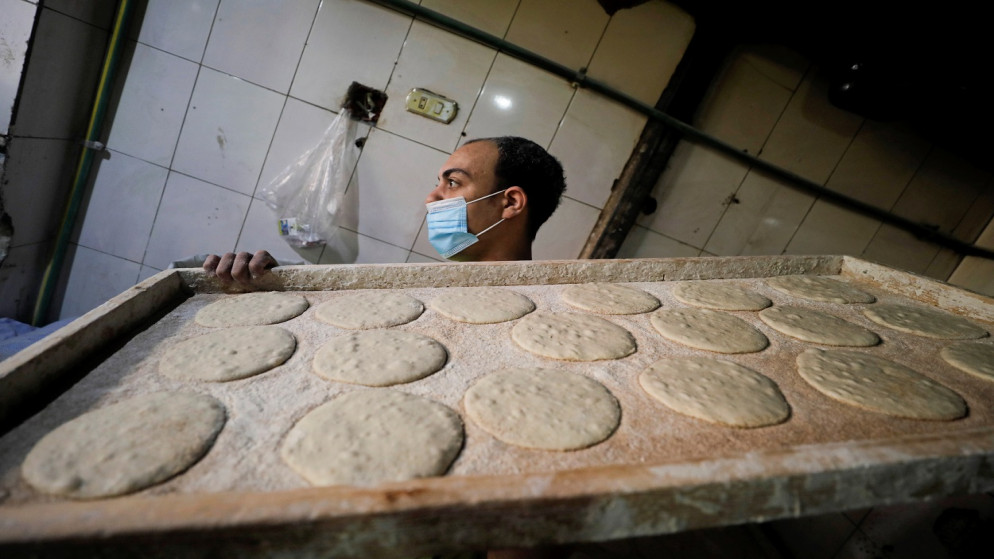 عامل يرتدي كمامة للوجه يحمل عجينًا ليتم وضعه في فرن بمخبز وسط جائحة فيروس كورونا، القاهرة، مصر 2021/2/25. (رويترز)