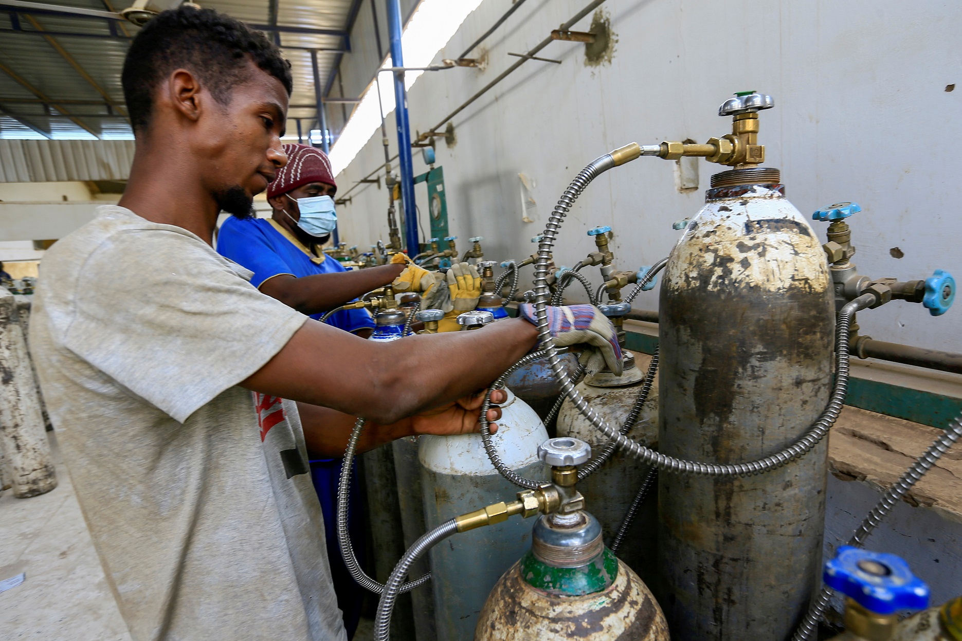 عمال يجهزون أسطوانات الأكسجين لمرضى فيروس كورونا داخل شركة الغاز السائل السودانية في الخرطوم، السودان ، 5 أيار/مايو 2021. (رويترز / محمد نور الدين عبد الله)
