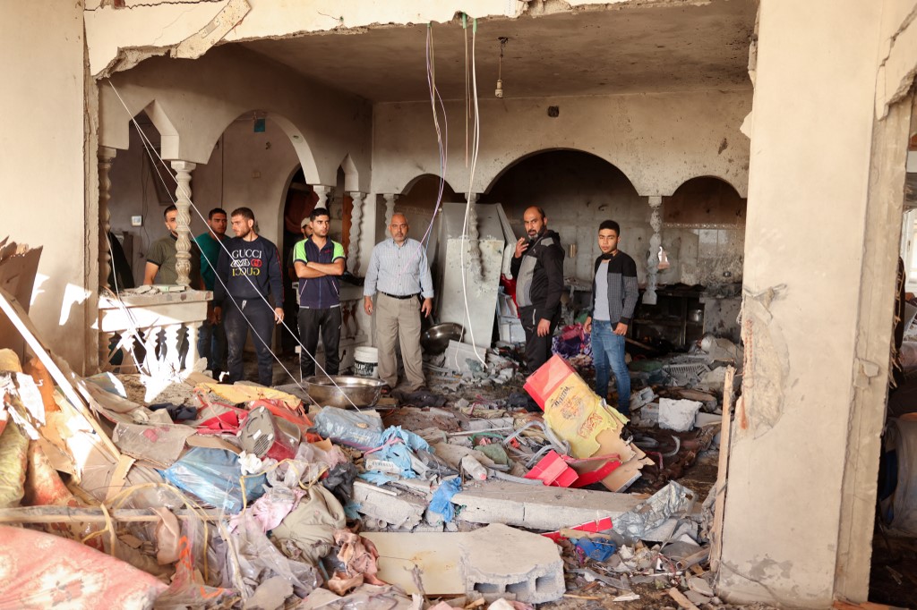 جيران وأقارب يقيّمون الأضرار التي لحقت بمنزل في دير البلح وسط قطاع غزة إثر العدوان الإسرائيلي عليه، 19 أيار/مايو 2021. (سيد خطيب/أ ف ب)