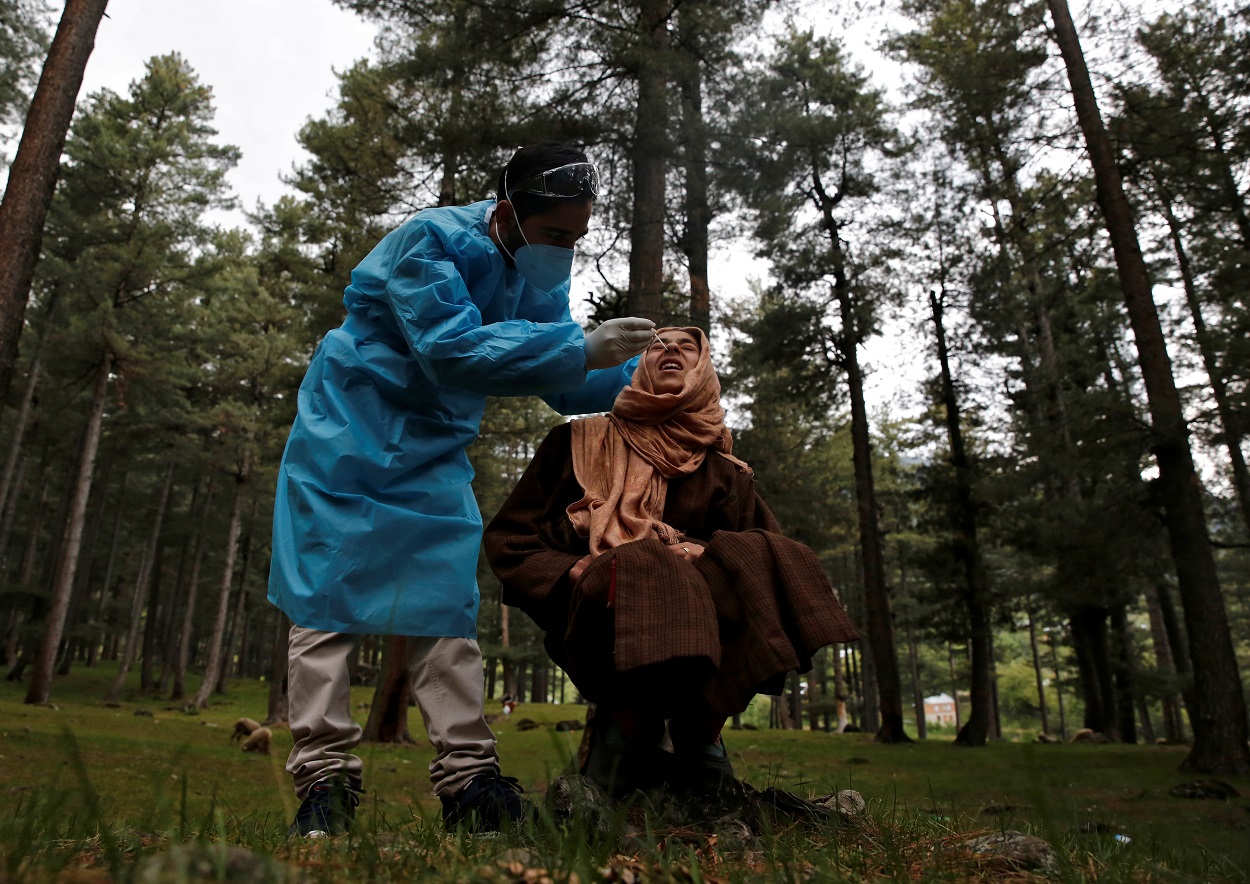 عامل رعاية صحية يأخذ عينة مسحة أنف من فتاة لاختبار فيروس كورونا، في قرية نوروز بابا في منطقة بودجام بوسط كشمير، 20 مايو 2021. (رويترز)