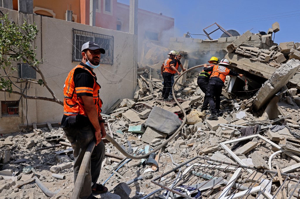 عمال إنقاذ فلسطينيون عند مبنى في أعقاب غارة جوية إسرائيلية على رفح في جنوب قطاع غزة، 20 أيار/مايو 2021. (أ ف ب)