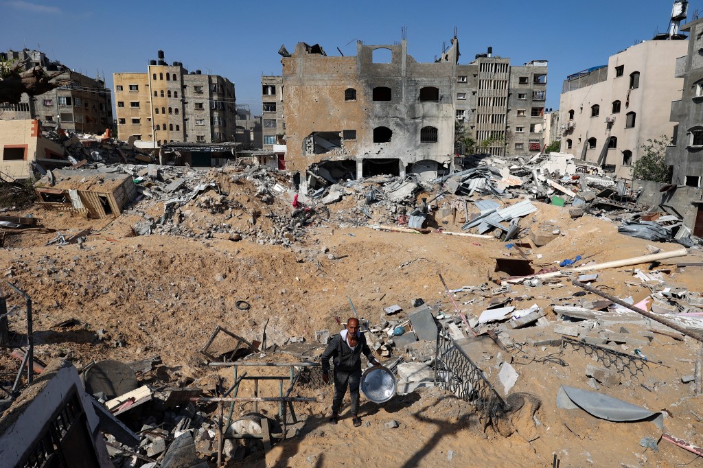 رجل يسير بجانب مبانٍ تعرضت لقصف إسرائيلي في قطاع غزة. (أ ف ب)