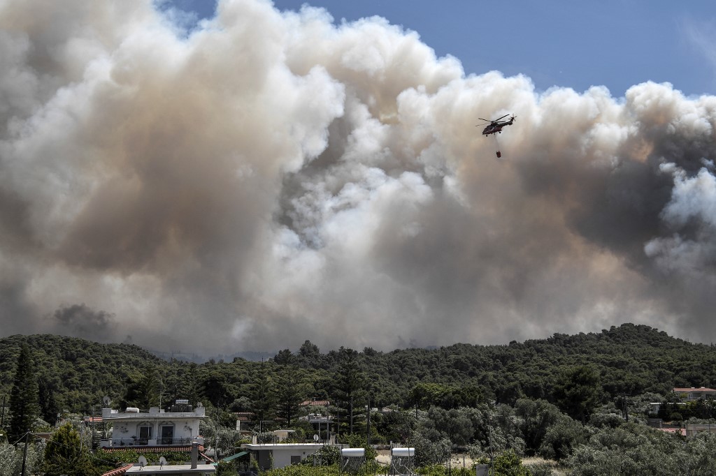 مروحية إطفاء تحلق فوق قرية البوشوري، بعد اندلاع حريق خلال الليل في سلسلة جبلية تطل على خليج كورينث، 20 مايو/أيار 2021. (أ ف ب)
