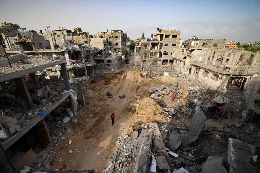 فلسطيني يسير في أحد الأحياء التي تعرضت للقصف الإسرائيلي في مدينة غزة، بعد وقف إطلاق النار، 21 مايو 2021. (أ ف ب)