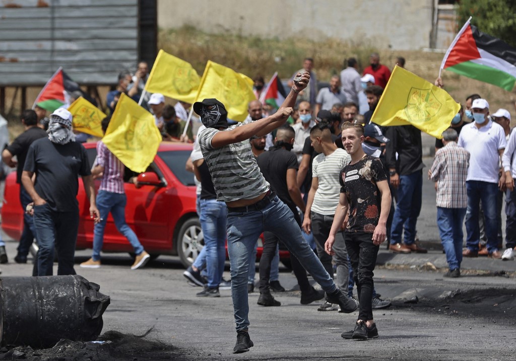 متظاهرون فلسطينيون يرشقون الحجارة وسط مواجهات مع قوات الأمن الإسرائيلية على حاجز حوارة جنوب مدينة نابلس في الضفة الغربية المحتلة . 21 مايو/أيار 2021. (أ ف ب)