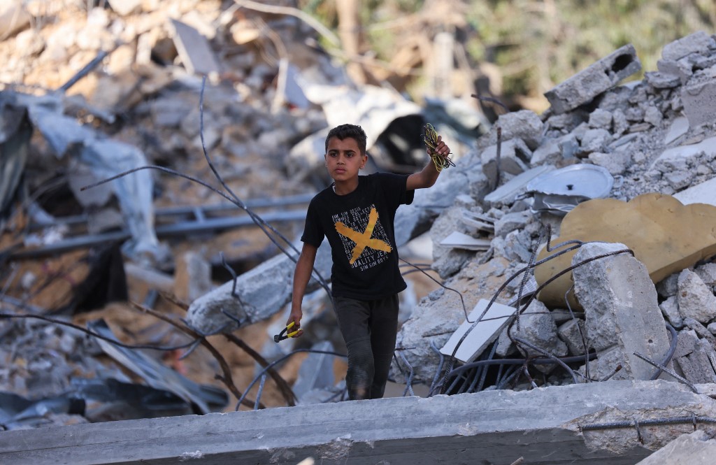 طفل فلسطيني يتفقد أنقاض المباني التي دمرتها الغارات الإسرائيلية في بيت لاهيا شمال قطاع غزة، 21 أيار/مايو 2021. (أ ف ب)