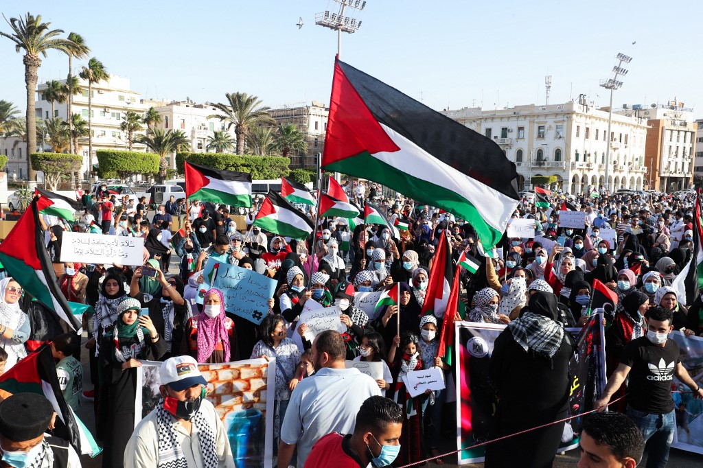 متظاهرون ليبيون يرفعون الأعلام واللافتات خلال مسيرة لدعم الفلسطينيين في ساحة الشهداء بالعاصمة طرابلس، 21 أيار/مايو 2021.(أ ف ب)