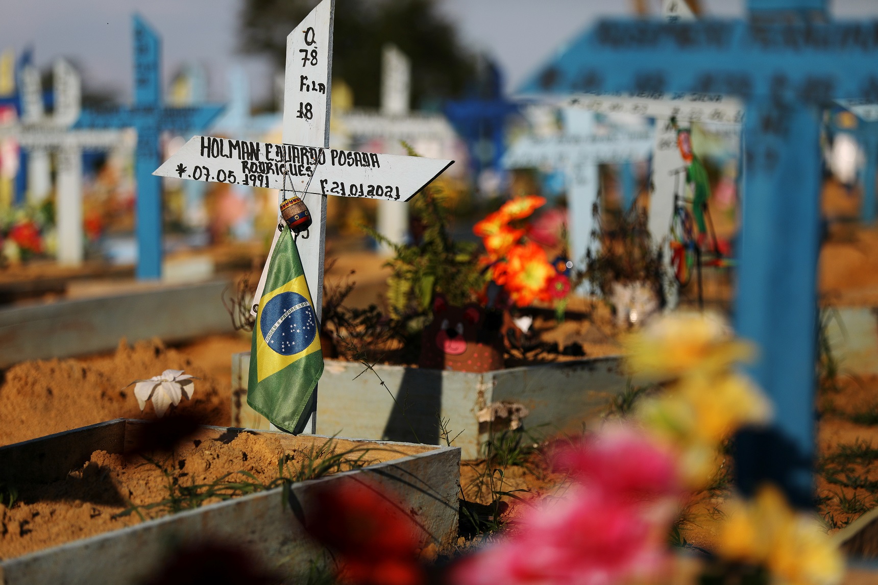علم برازيلي على قبر شخص مات بسبب فيروس كورونا في مقبرة باركي تاروما في ماناوس، البرازيل، 20 أيار/مايو 2021. (رويترز / برونو كيلي)