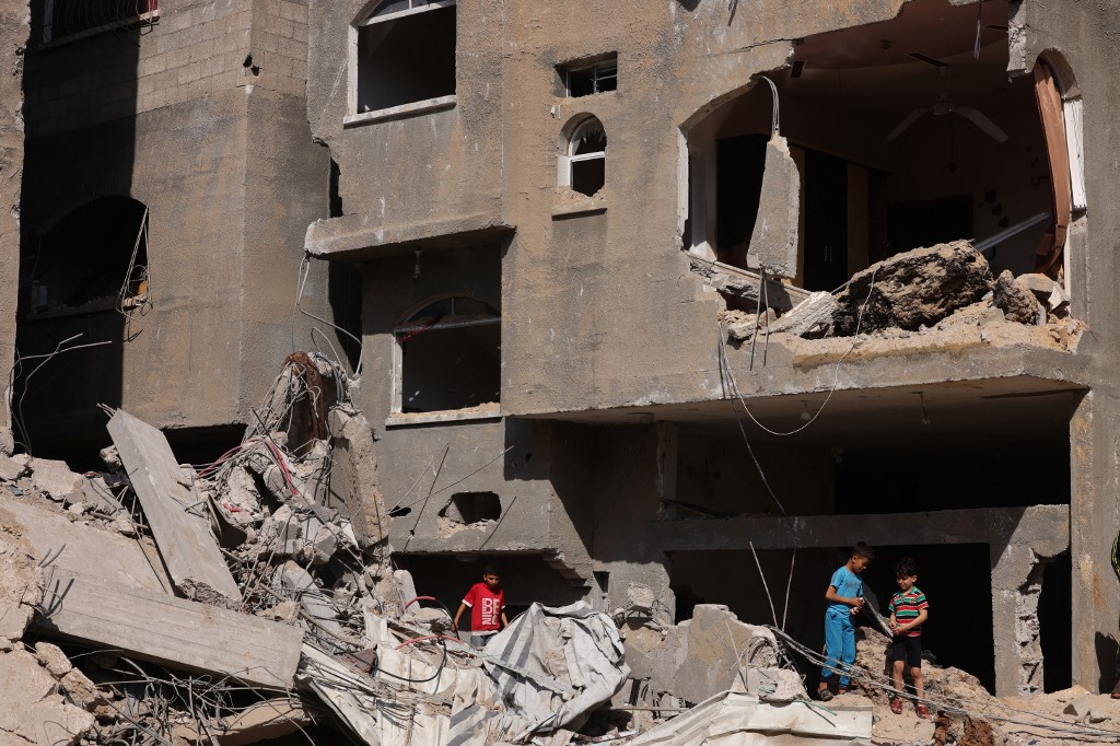 أطفال فلسطينيون بجانب مبنى مدمر بعد قصف لقوات الاحتلال الإسرائيلي على قطاع غزة. (أ ف ب)