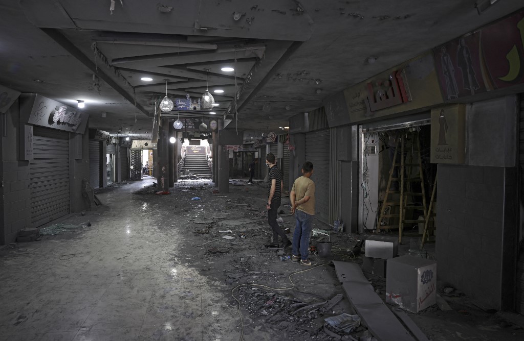 فلسطينيون يتفقدون الدمار في مركز تجاري ، بعد هجوم إسرائيلي ، في مدينة غزة في 22 مايو/أيار ، 2021. (أ ف ب)