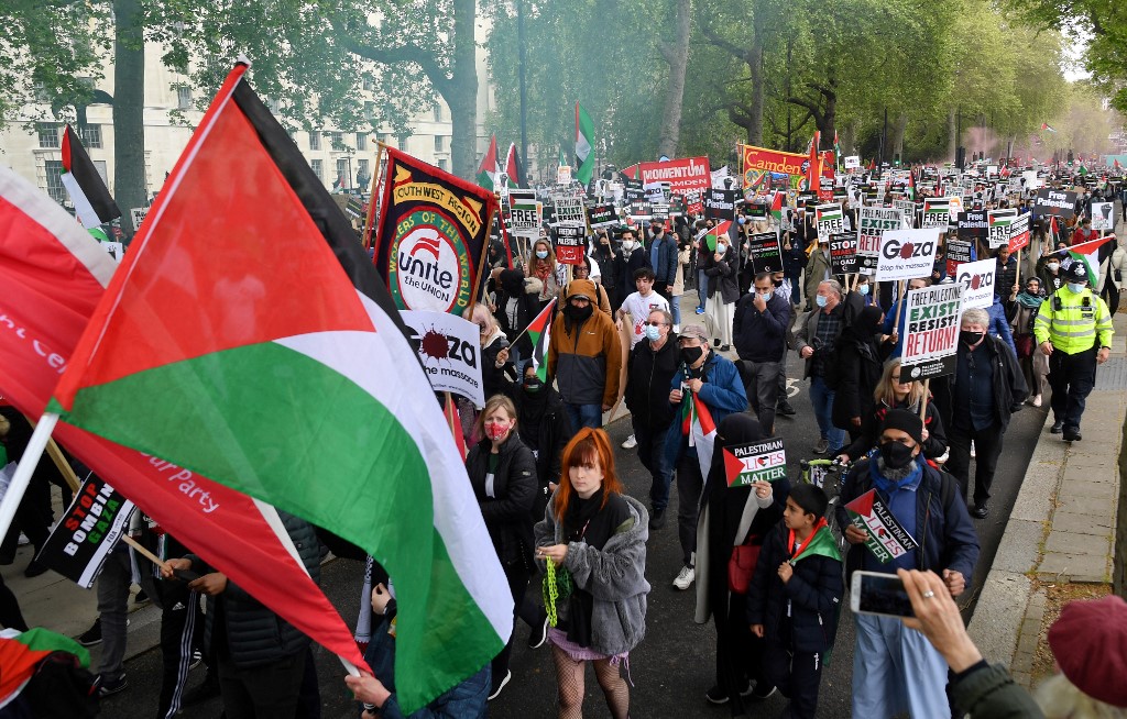 متظاهرون مؤيدون لفلسطين يحملون لافتات أثناء مسيرة إلى ساحة البرلمان في وسط لندن .22 مايو/أيار 2021.(أ ف ب)