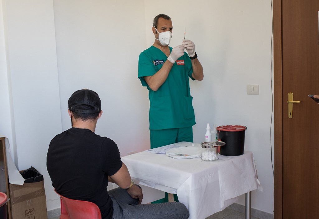 عامل طبي في مركز تطعيم يستعد لإعطاء جرعة من لقاح موديرنا لمحاربة فيروس كورونا في إيطاليا. (أ ف ب)