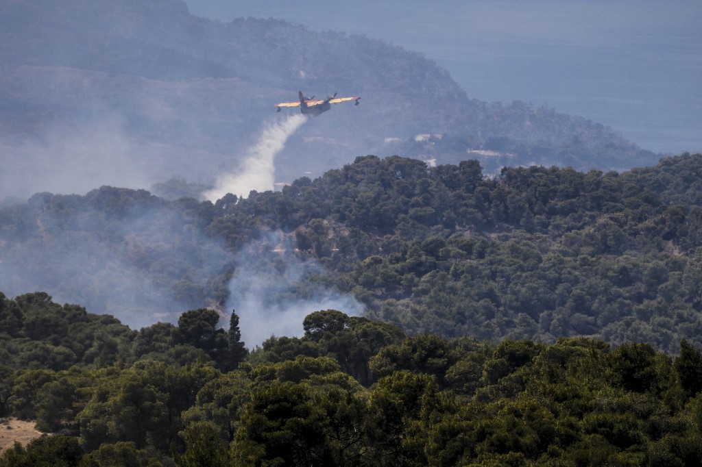 طائرة لمكافحة الحرائق ترش مياه لإخماد حريق هائل في جبل ييرانيا غرب أثينا في اليونان. 22/05/2021. (أ ف ب)