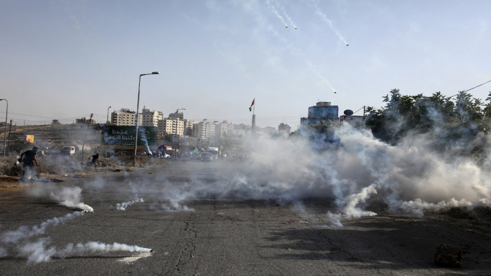 متظاهرون فلسطينيون يندفعون مع سقوط قنابل الغاز المسيل للدموع وسط اشتباكات مع قوات الأمن الإسرائيلية بالقرب من مستوطنة بيت إيل بالقرب من رام الله في الضفة الغربية المحتلة .21 مايو/أيار 2021.(أ ف ب)