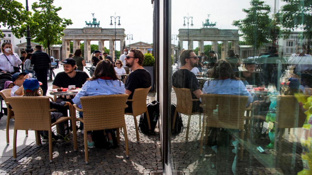 أشخاص يجلسون في مقهى بالقرب من بوابة براندنبورغ في برلين حيث سُمح للمطاعم والمقاهي باستئناف العمل في الهواء الطلق ، وسط جائحة فيروس كورونا (كوفيد -19).24 مايو 2021. (أ ف ب)