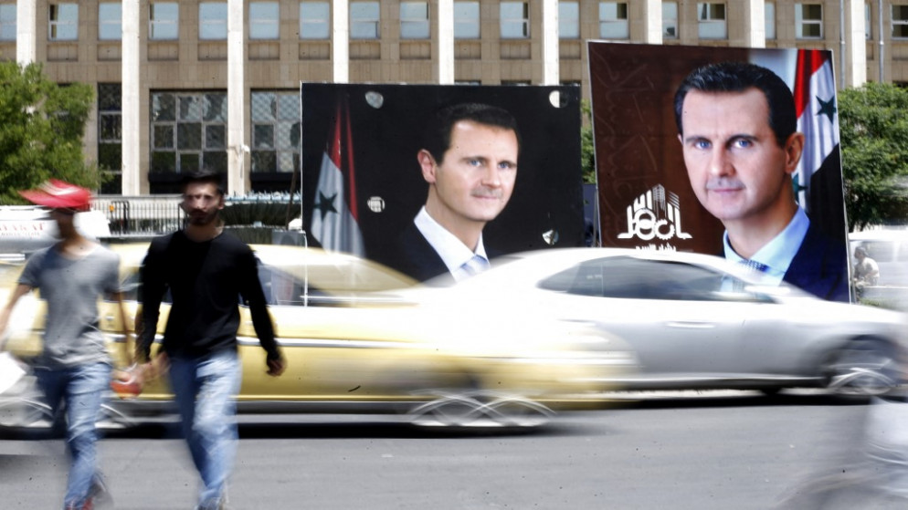 أشخاص يسيرون بجانب لوحات إعلانية انتخابية يظهر بها الرئيس السوري بشار الأسد المرشح للانتخابات الرئاسية المقبلة في العاصمة دمشق .24 مايو 2021.(أ ف ب)
