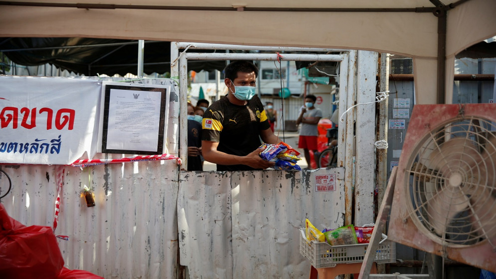 العمال المهاجرون يشترون من ميانمار وجبات خفيفة من أحد البائعين بعد أن علقوا بسبب الإغلاقات في مهجع العمال في بانكوك، تايلاند، 24/5/2021. (رويترز)