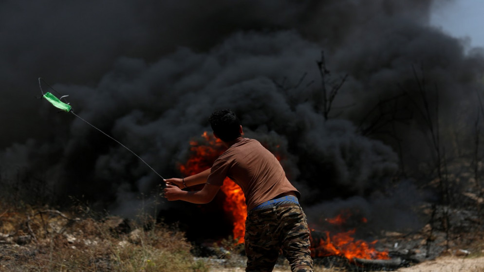 شاب فلسطيني يلقي الحجارة خلال مواجهات مع قوات الاحتلال الإسرائيلي. (أ ف ب)