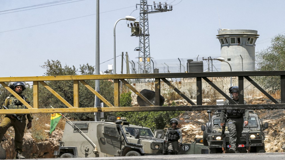 جنود وحرس الحدود الإسرائيليين يقفون عند مدخل حاجز مغلق يؤدي إلى قرية نعلين الفلسطينية غربي رام الله في الضفة الغربية المحتلة . 29 مايو/أيار 2021. (أ ف ب)