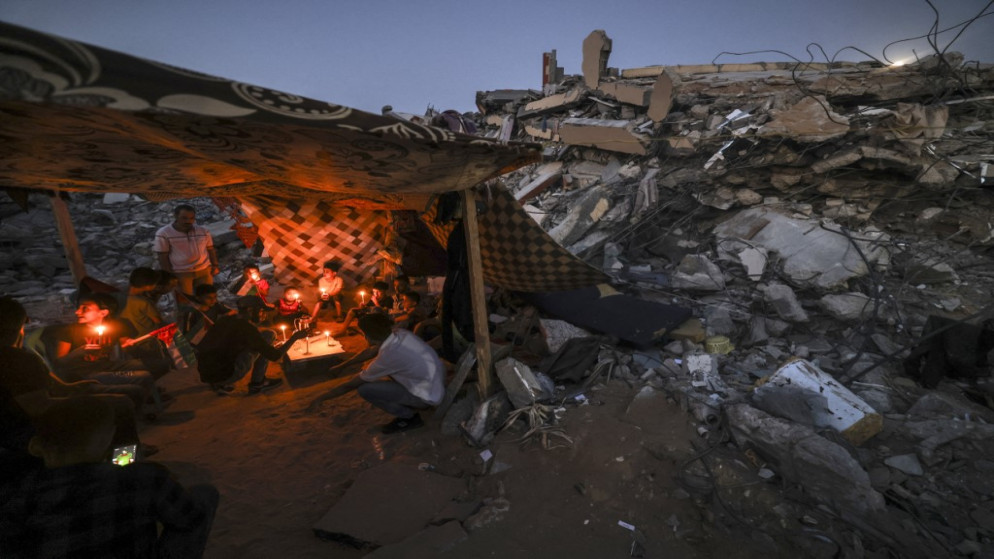 فلسطينيون يجلسون في خيمة أقيمت على أنقاض مبنى دمر في الغارات الجوية الإسرائيلية الأخيرة ، في بيت لاهيا شمال قطاع غزة . 25 مايو 2021. (أ ف ب)