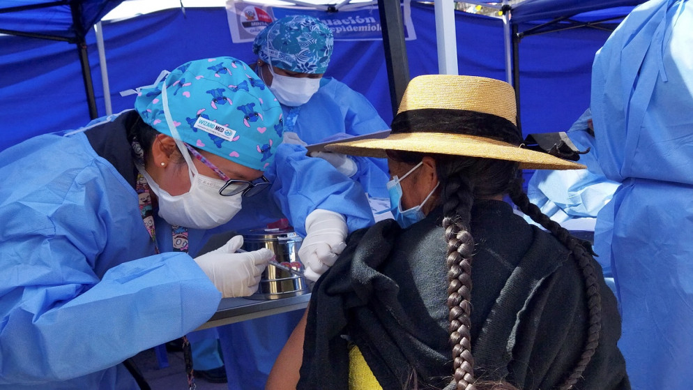 امرأة بيروفية تتلقى لقاح ضد مرض فيروس كورونا، حيث بدأت السلطات بتلقيح الأشخاص الذين يكسبون عيشهم عبر الحدود بين بوليفيا وبيرو، في ديساجواديرو، بيرو، 21 مايو 2021. (رويترز)