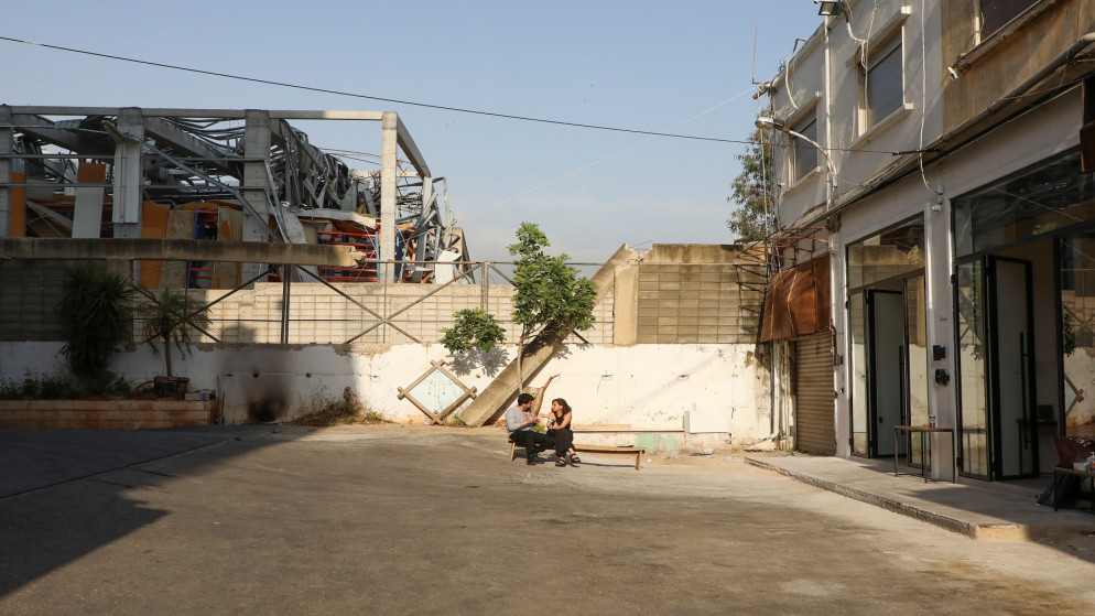أشخاص يجلسون خارج صالة عرض فنية أعيد فتحها بعد أن تضررت بسبب الانفجار الهائل في منطقة ميناء بيروت. ، لبنان. 21 مايو 2021.(رويترز)