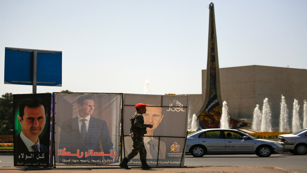 ضابط في الشرطة العسكرية السورية يمر من أمام ملصقات تصور الرئيس السوري بشار الأسد ، خلال الانتخابات الرئاسية السورية في دمشق.(رويترز)