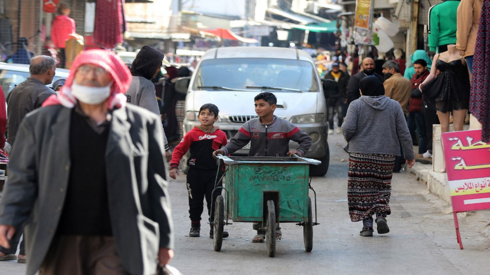 طفلان يستخدمان عربة يدوية للعمل في منطقة الوحدات في عمّان، 10 كانون الثاني/يناير 2021. (خليل مزرعاوي/ أ ف ب)