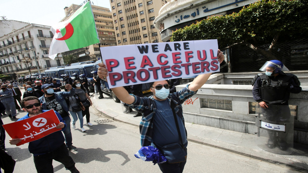 صورة أرشيفية لمتظاهرين يسيرون باللافتات والأعلام خلال مظاهرة للمطالبة بالتغيير السياسي في الجزائر العاصمة (رويترز / رمزي بودينا)
