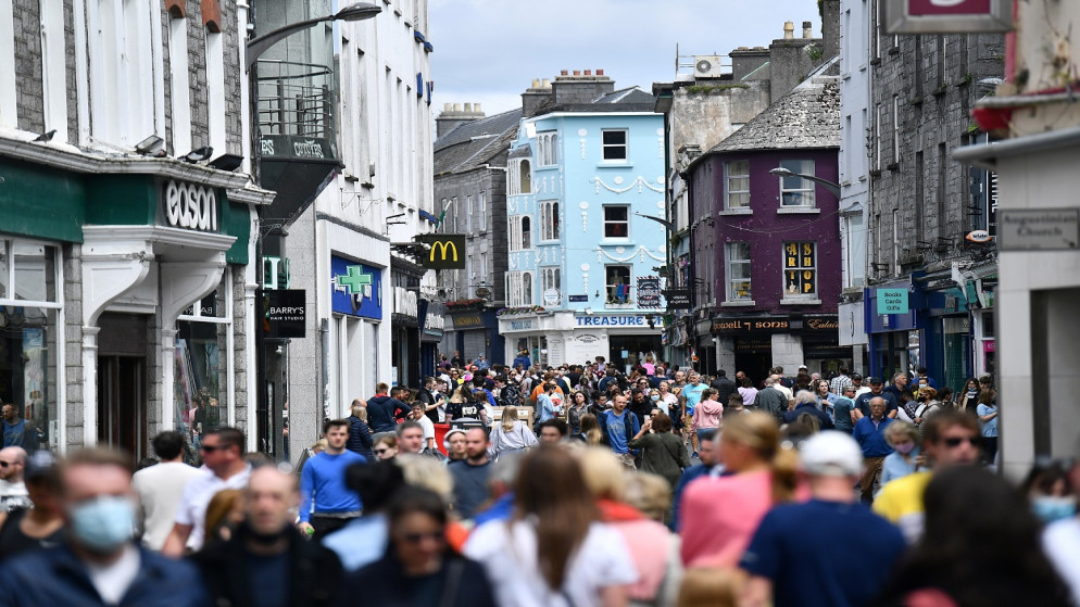 أشخاص يسيرون في الخارج مع استئناف الخدمات في الهواء الطلق في المطاعم، مع تخفيف القيود في أعقاب تفشي فيروس كورونا، في غالواي، أيرلندا، 7 يونيو 2021. (رويترز)