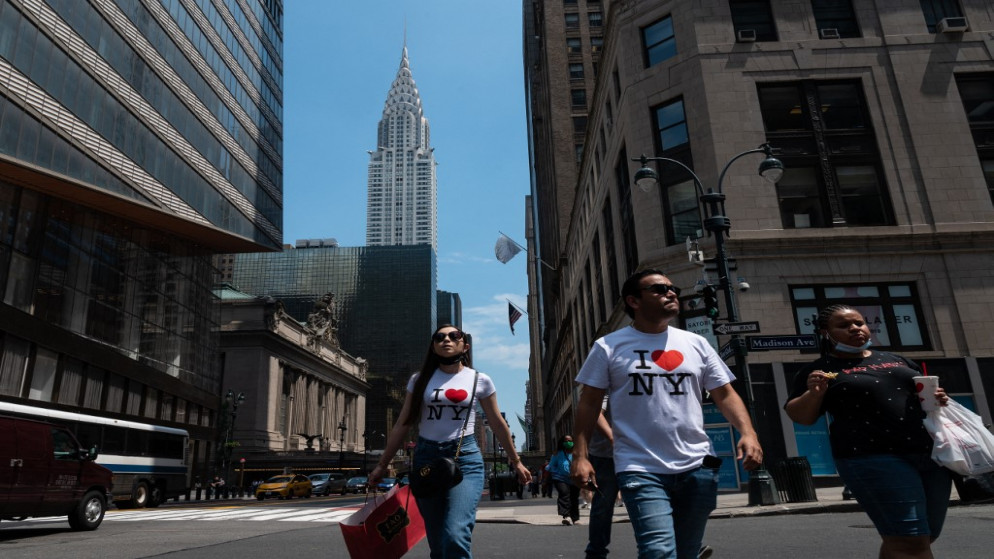 أشخاص يسيرون بجوار مبنى كرايسلر في يوم دافئ في 7 يونيو 2021 في مدينة نيويورك. (أ ف ب)