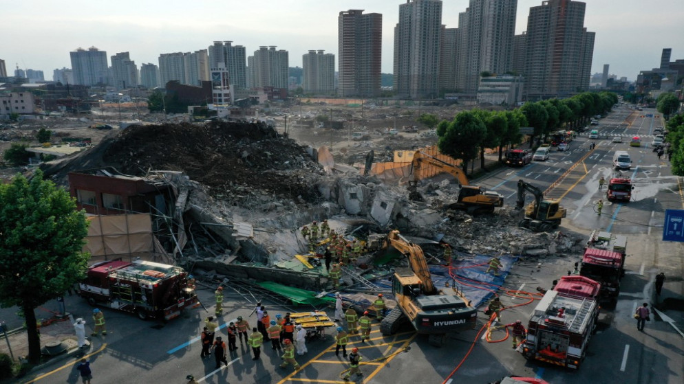 عمال إنقاذ يبحثون عن ناجين محتملين من حطام مبنى منهار في كوانغجو، 9 يونيو 2021. (أ ف ب)