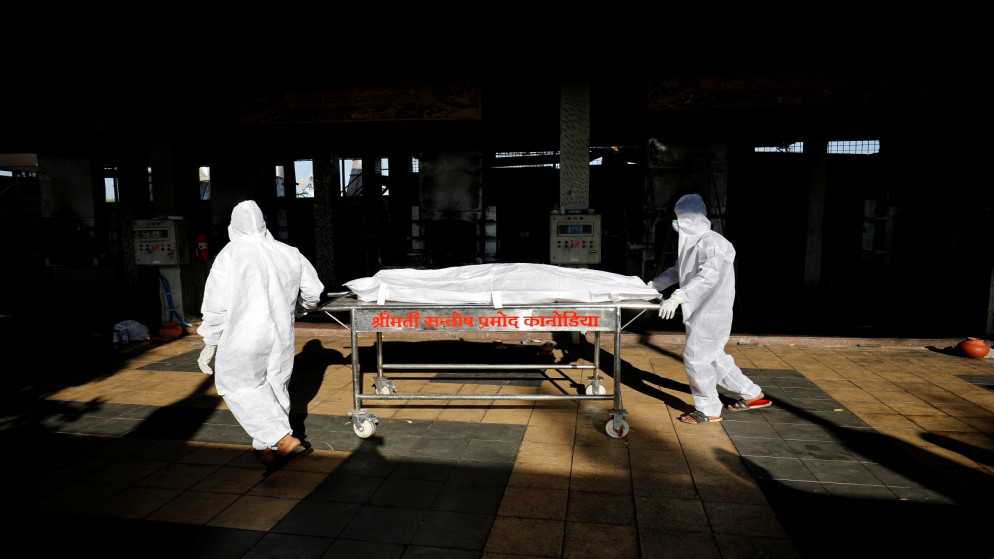 عمال ينقلون جثة شخص مات بسبب فيروس كورونا في سورات، الهند، 11 أيار/مايو 2021. (رويترز / أميت ديف)