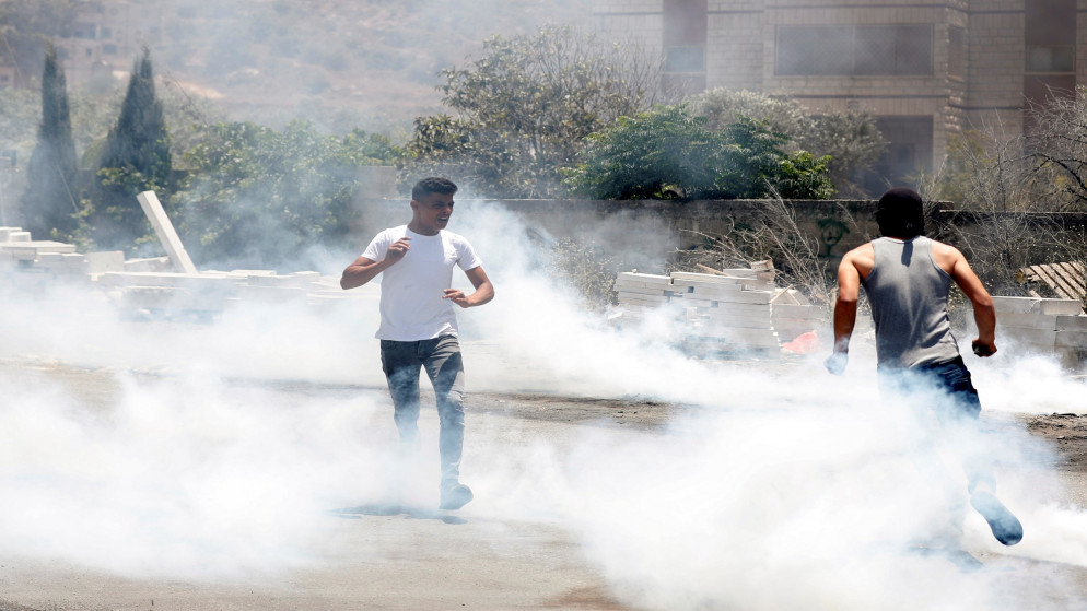 فلسطينيان بعد إطلاق قوات الاحتلال الإسرائيلي قنابل الغاز في الضفة الغربية المحتلة. (رويترز)
