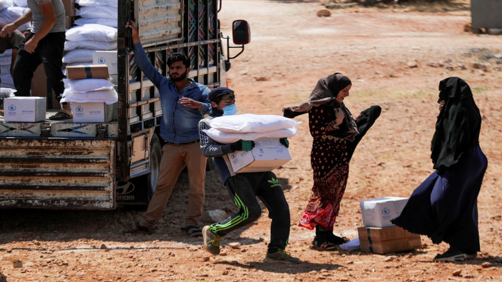 عامل يحمل أكياسا وصندوقا من المساعدات الإنسانية في مدينة إدلب السورية الخاضعة لسيطرة المعارضة، 9 حزيران/يونيو 2021. (رويترز)