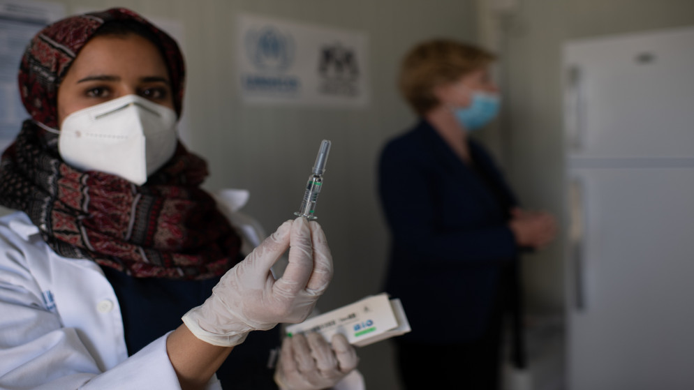 ممرضة تحمل جرعة لقاح مضاد لفيروس كورونا في أحد مخيمات اللاجئين السوريين في الأردن. (مفوضية الأمم المتحدة لشؤون اللاجئين)